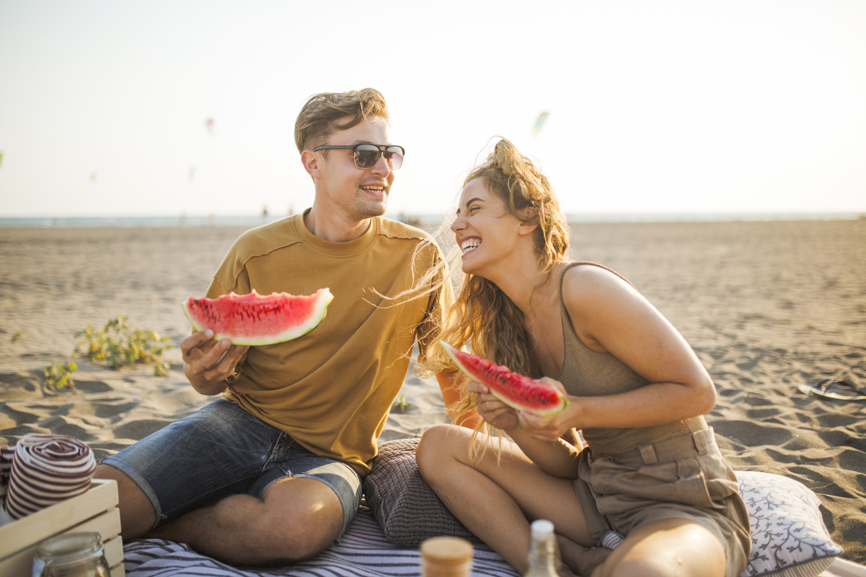 jóvenes en la playa comiendo sandia