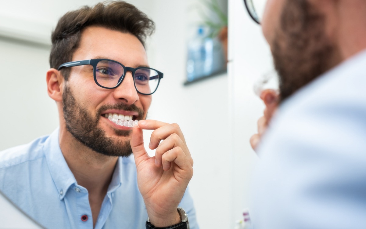 hombre en espejo probándose funda dental