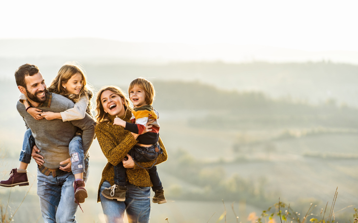 pareja llevando a sus hijos en brazos por el campo