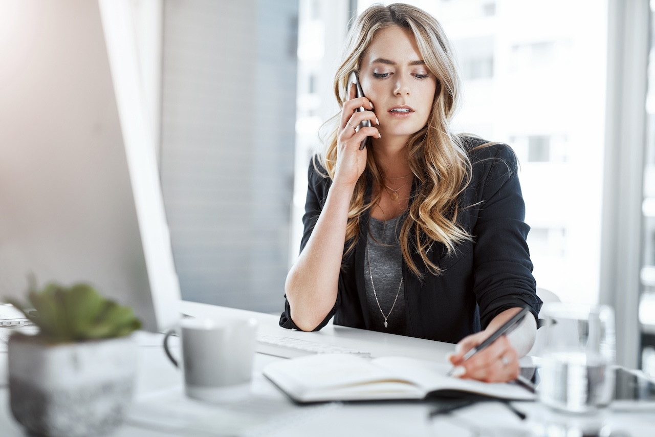 mujer en escritorio llamando por teléfono