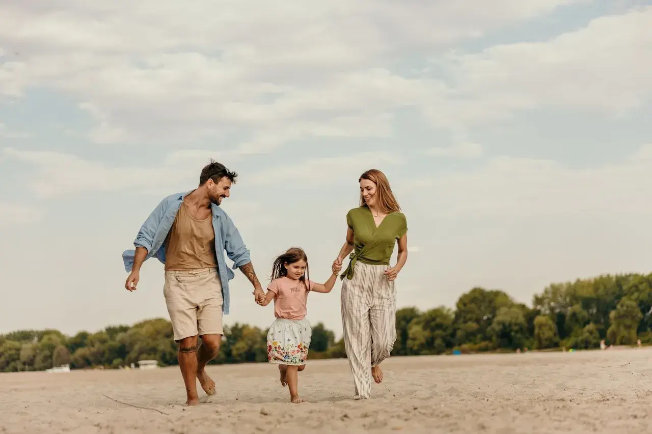 familia con hija pequeña corriendo por la playa