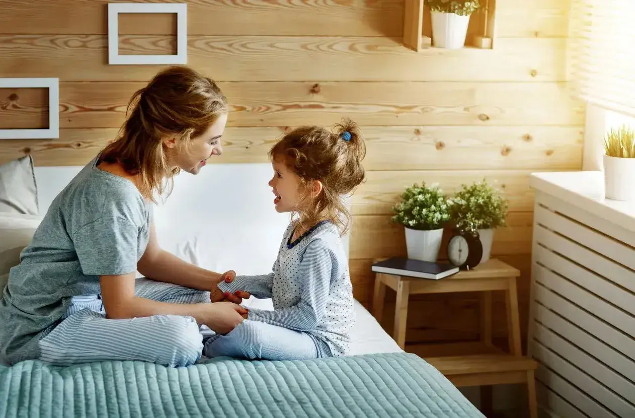 madre e hija sentadas encima de la cama